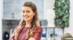 Smiling, confident woman with arms crossed in office