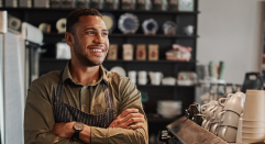 Smiling, confident man with arms crossed in coffeehouse