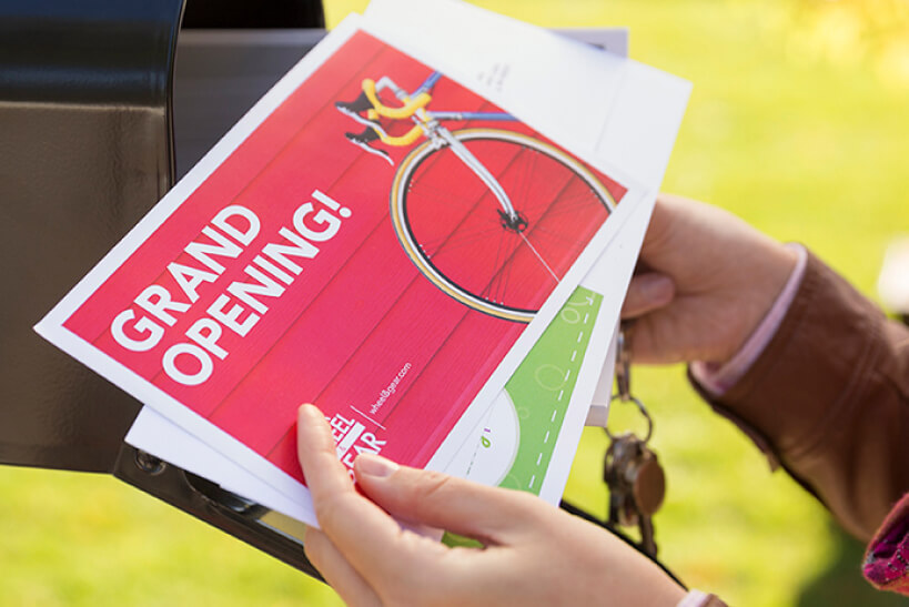 Image of mail being pulled from a mailbox with 'Grand Opening' on the top postcard